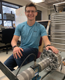FluxWorks founder seated beside a magnetic gear prototype in a lab